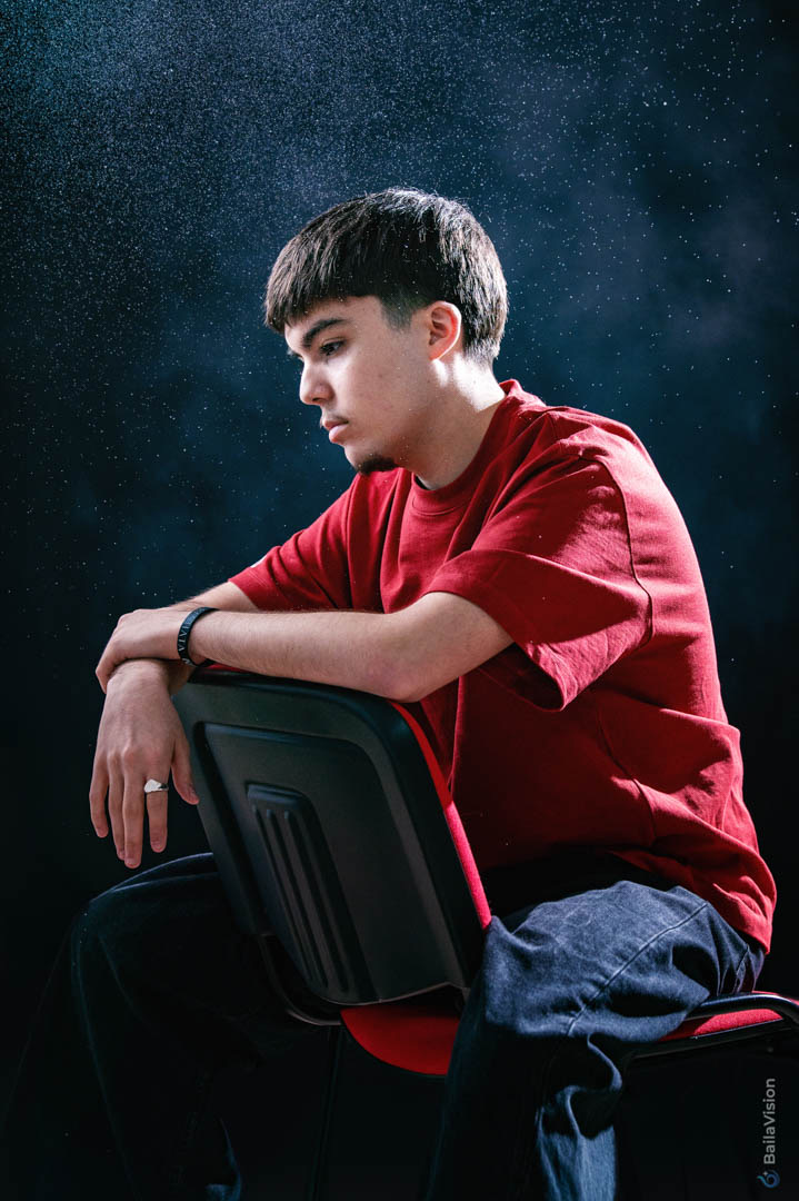 Portrait studio d’un artiste assis sur une chaise sous une lumière graphique